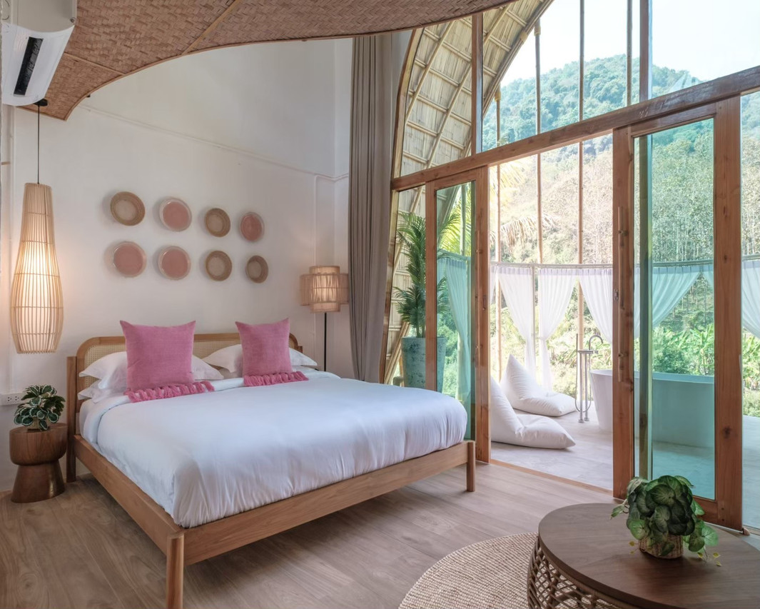 Villa with a curved bamboo roof, pale walls and floor-to-ceiling windows onto the mountains at Phu Ka Na Nan Resort