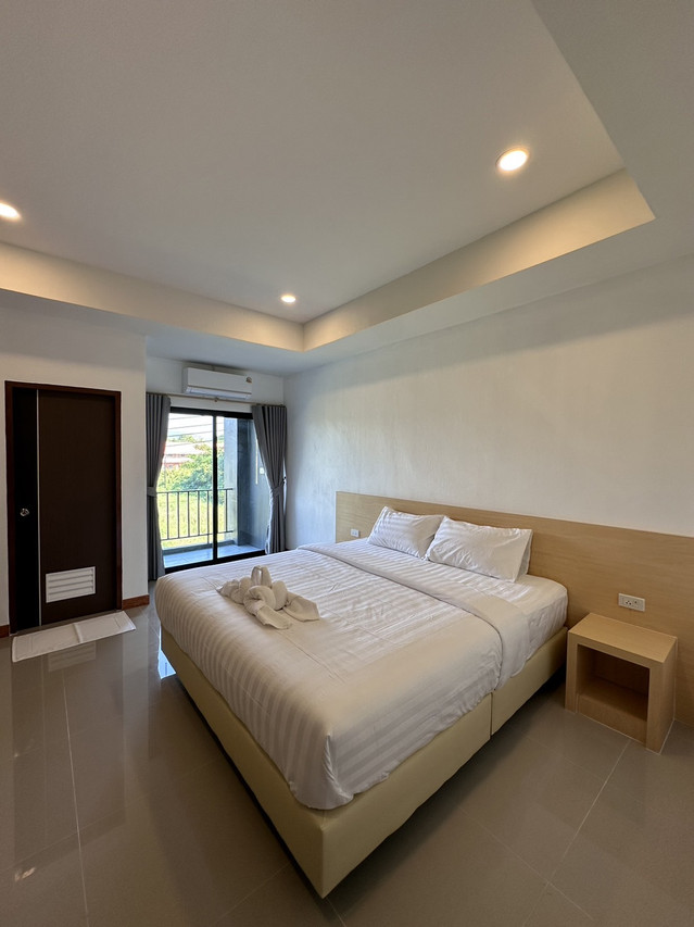 ห้องเตียงใหญ่ มีระเบียง แอร์ และมุมนั่งเล่นสว่างๆ