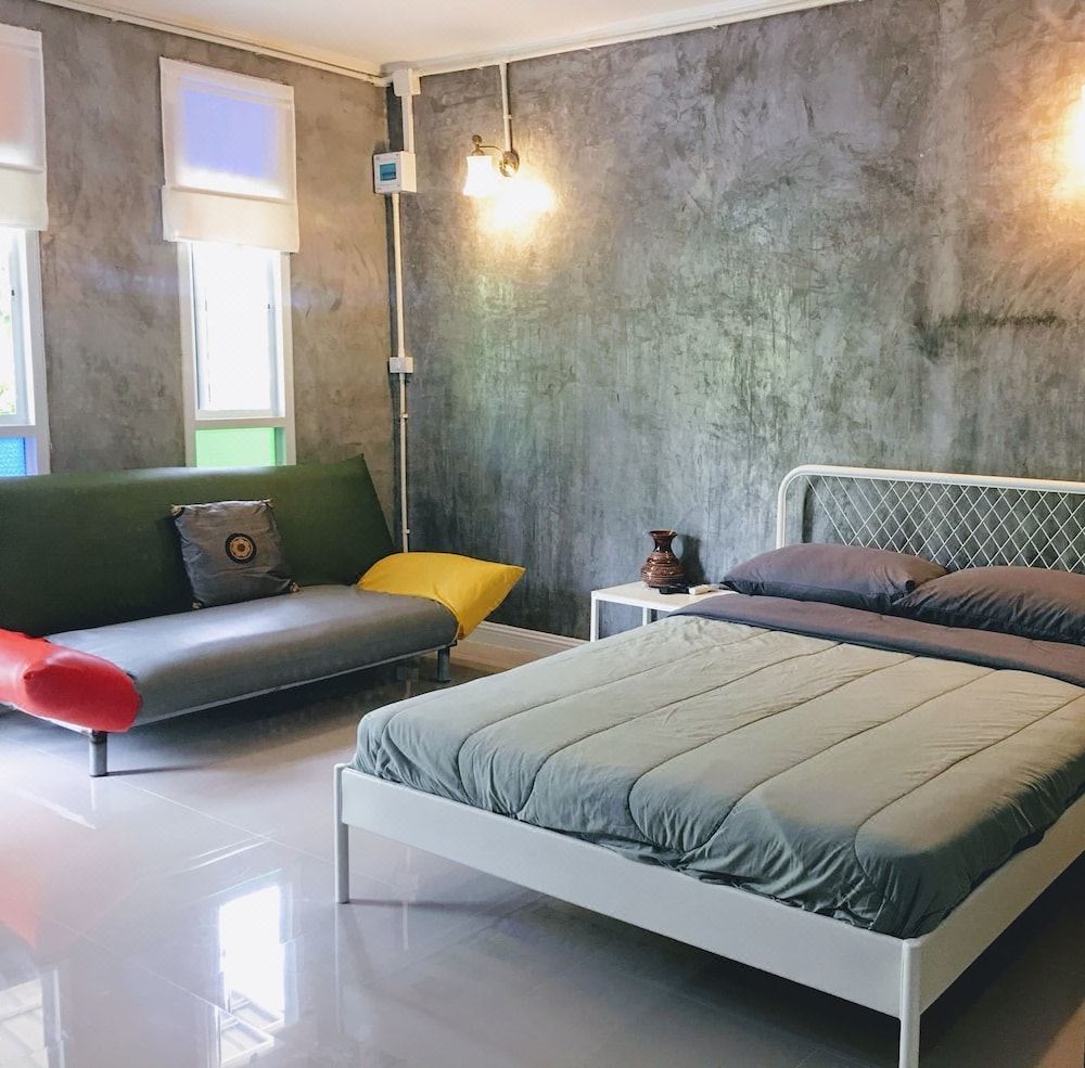 ห้องพัก Nongbualamphu Signature ผนังปูนเปลือยขัดมัน เตียงใหญ่และโซฟา พื้นกระเบื้องมันวาว