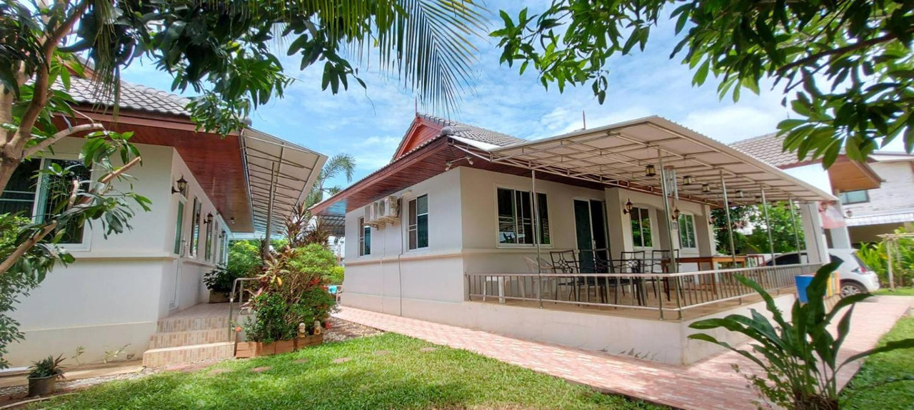 อาคารบ้านพักหลังคาทรงไทยสีขาวในสวนเขียวของ Nuch's Apple Guest House