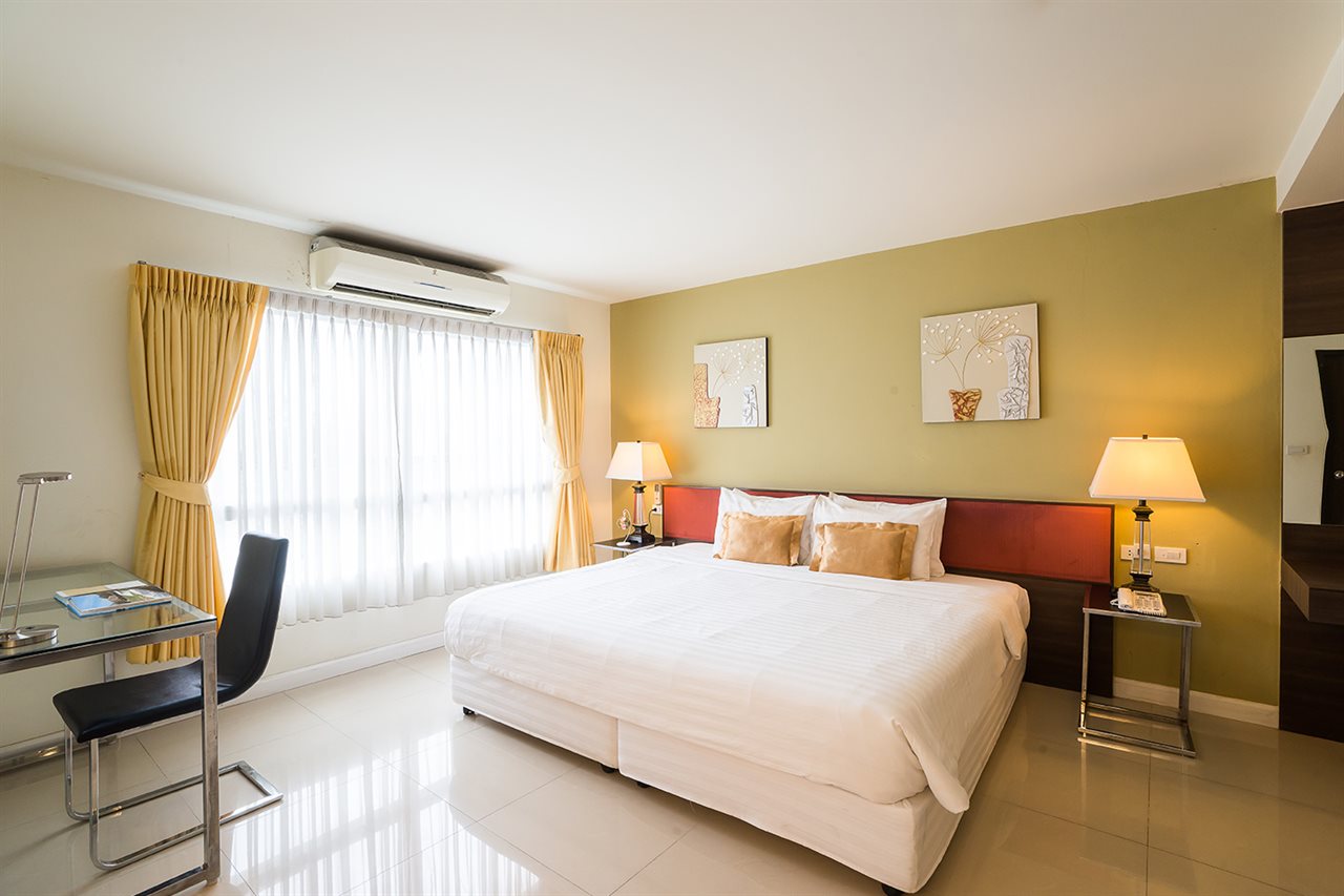 ห้องพัก Beyond Suite Hotel เตียงใหญ่ ผนังโทนเขียวมะกอก ม่านสีเหลือง