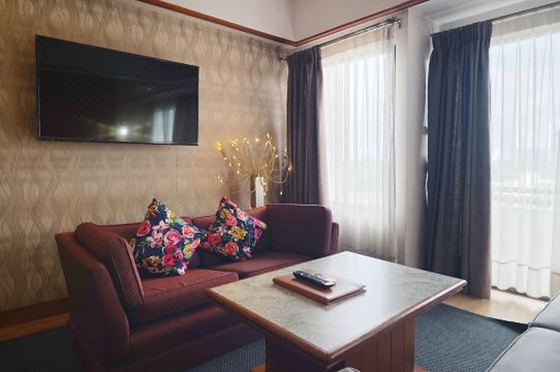ห้องนั่งเล่นแบบ Junior Suite โซฟา ทีวี และระเบียงรับแสง