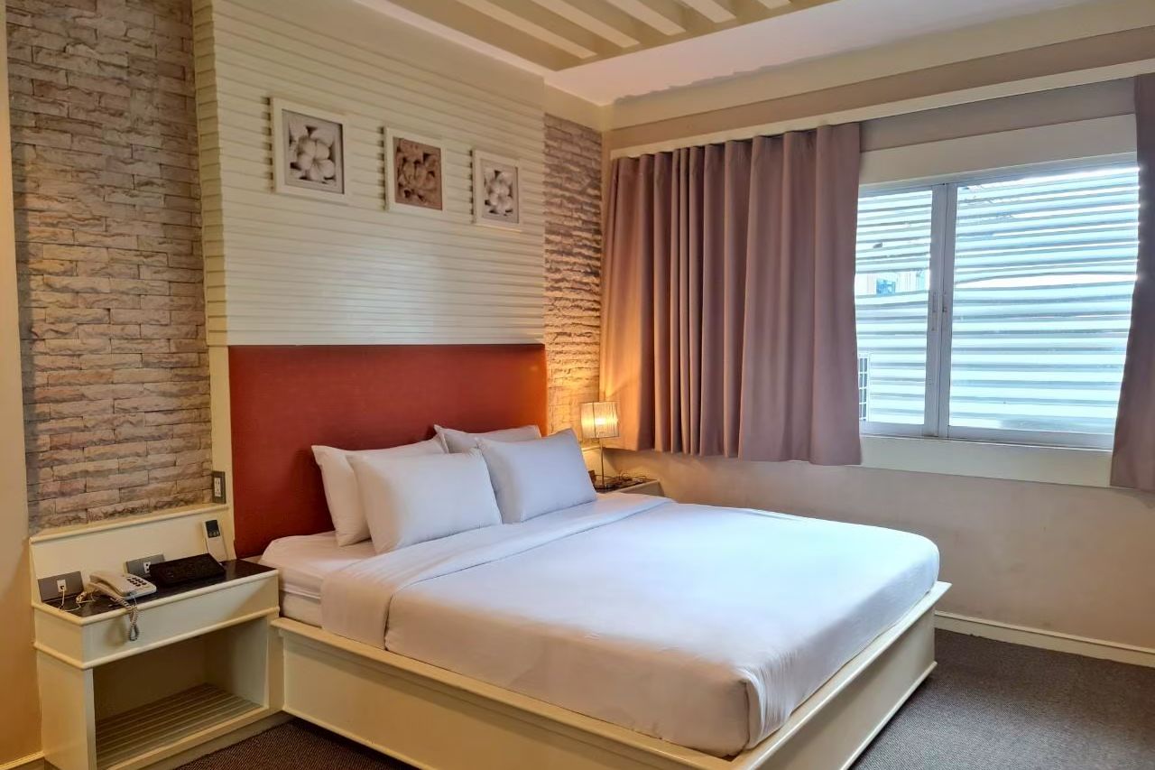 ห้องเตียงใหญ่ ผนังหินเทียม โทนอบอุ่นของ The Rich Hotel นนทบุรี