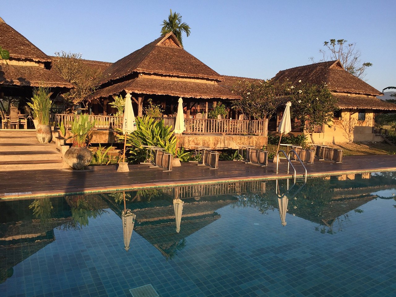 อาคารร้านอาหารหลังคามุงจากสะท้อนเงาในสระ infinity ยามเย็น Phu Pai Art Resort