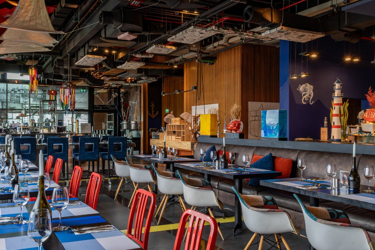 ร้านอาหารสไตล์ industrial-loft เพดานท่อเปลือยและเก้าอี้สีสันสดใส
