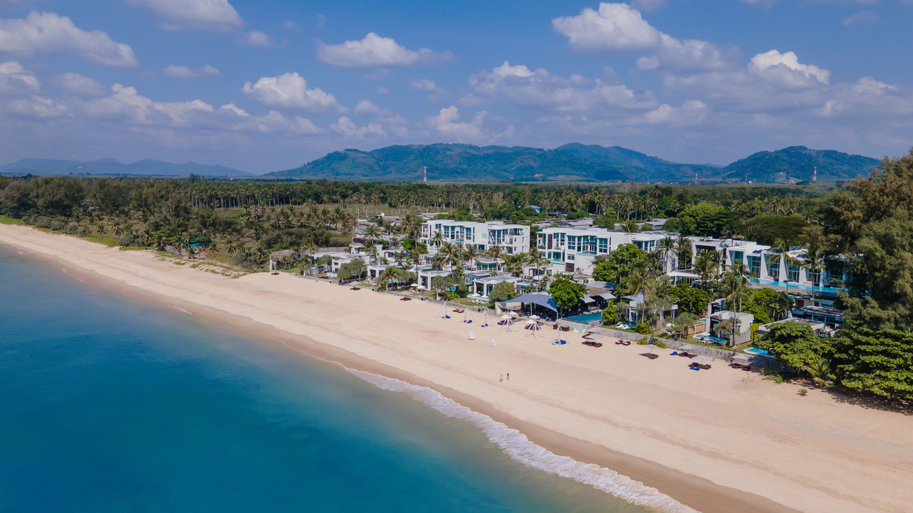 มุมสูงแสดง Aleenta Phuket-Phang Nga วิลล่าสีขาวเรียงตามแนวหาดนาใต้