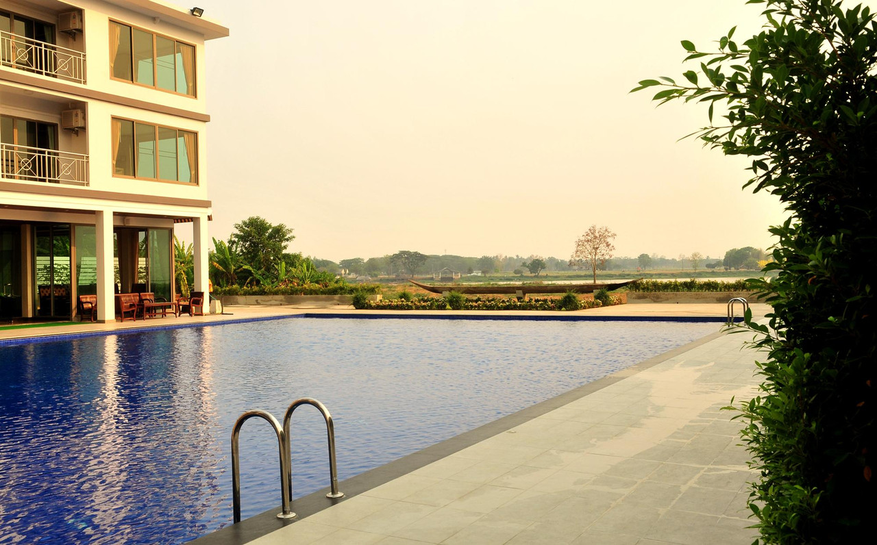 สระว่ายน้ำกลางแจ้งของ Green Hill Hotel Phayao มองข้ามทุ่งไปทางกว๊านพะเยา