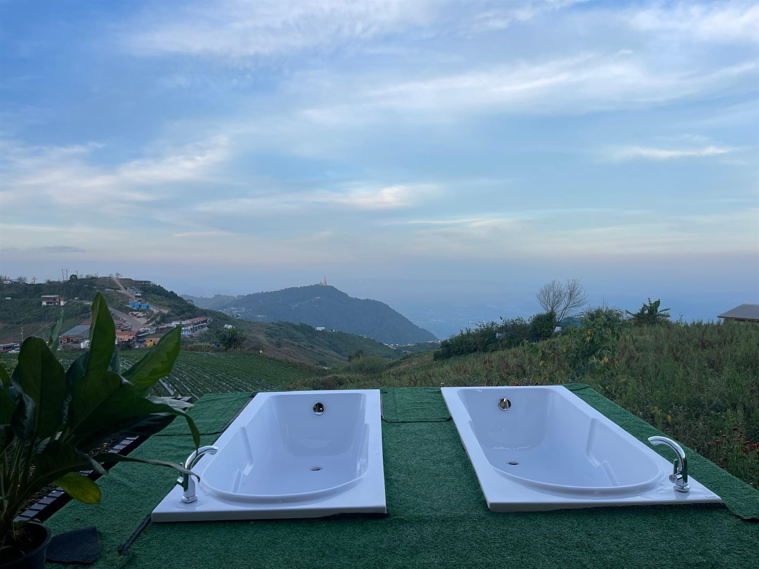Two open-air bathtubs on the ridge facing the hills and the distant Wat Pha Sorn Kaew pagoda