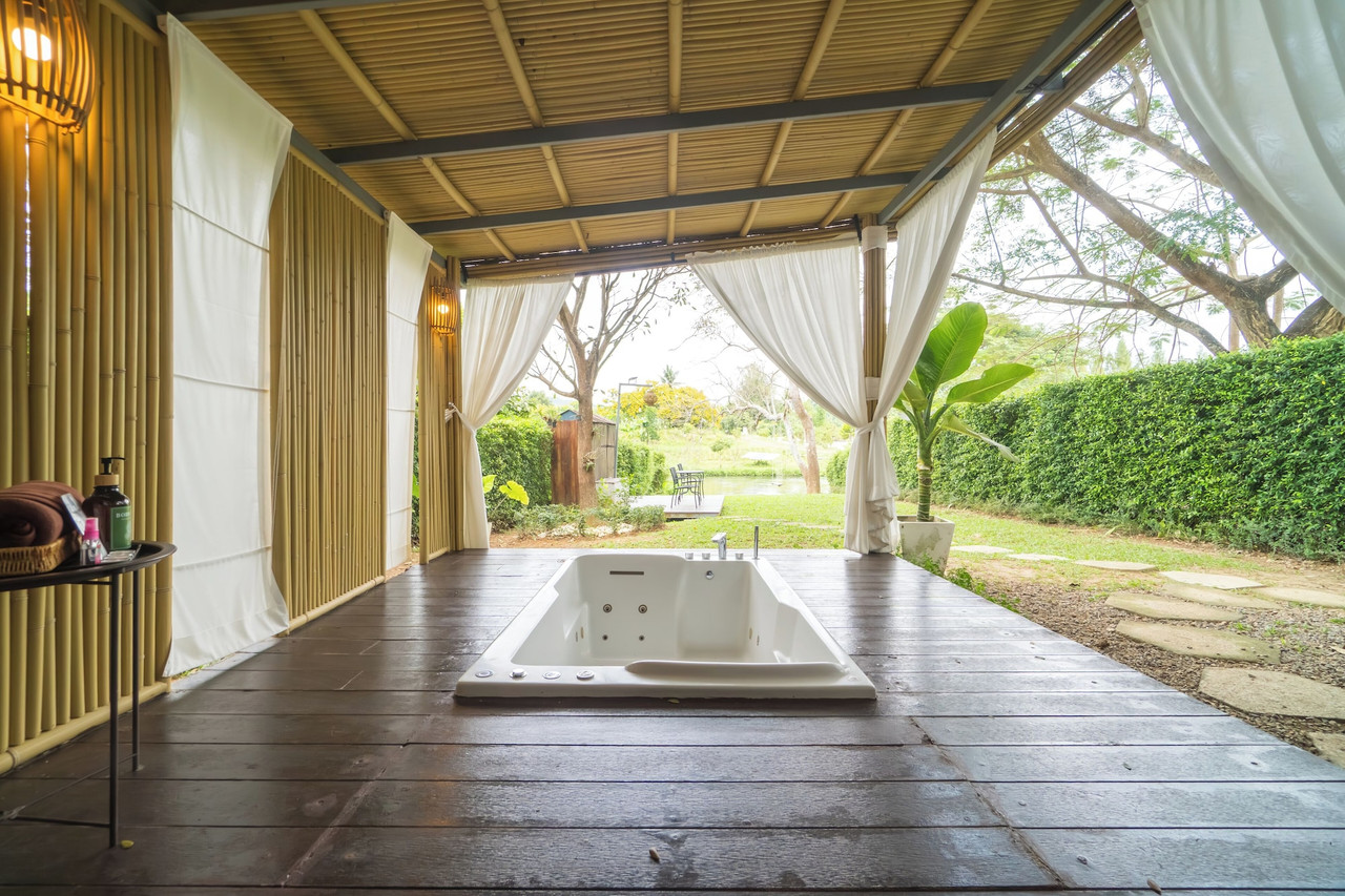 อ่างจากุซซี่กลางแจ้งของ Pool Villa มองออกไปเห็นสวนและแนวแม่น้ำ