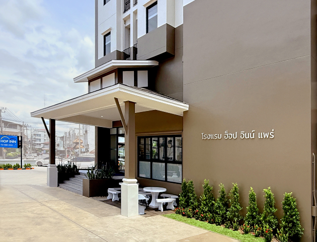 ทางเข้า Hop Inn Phrae มีป้ายภาษาไทย โรงแรมฮ็อป อินน์ แพร่ และที่นั่งหน้าโรงแรม