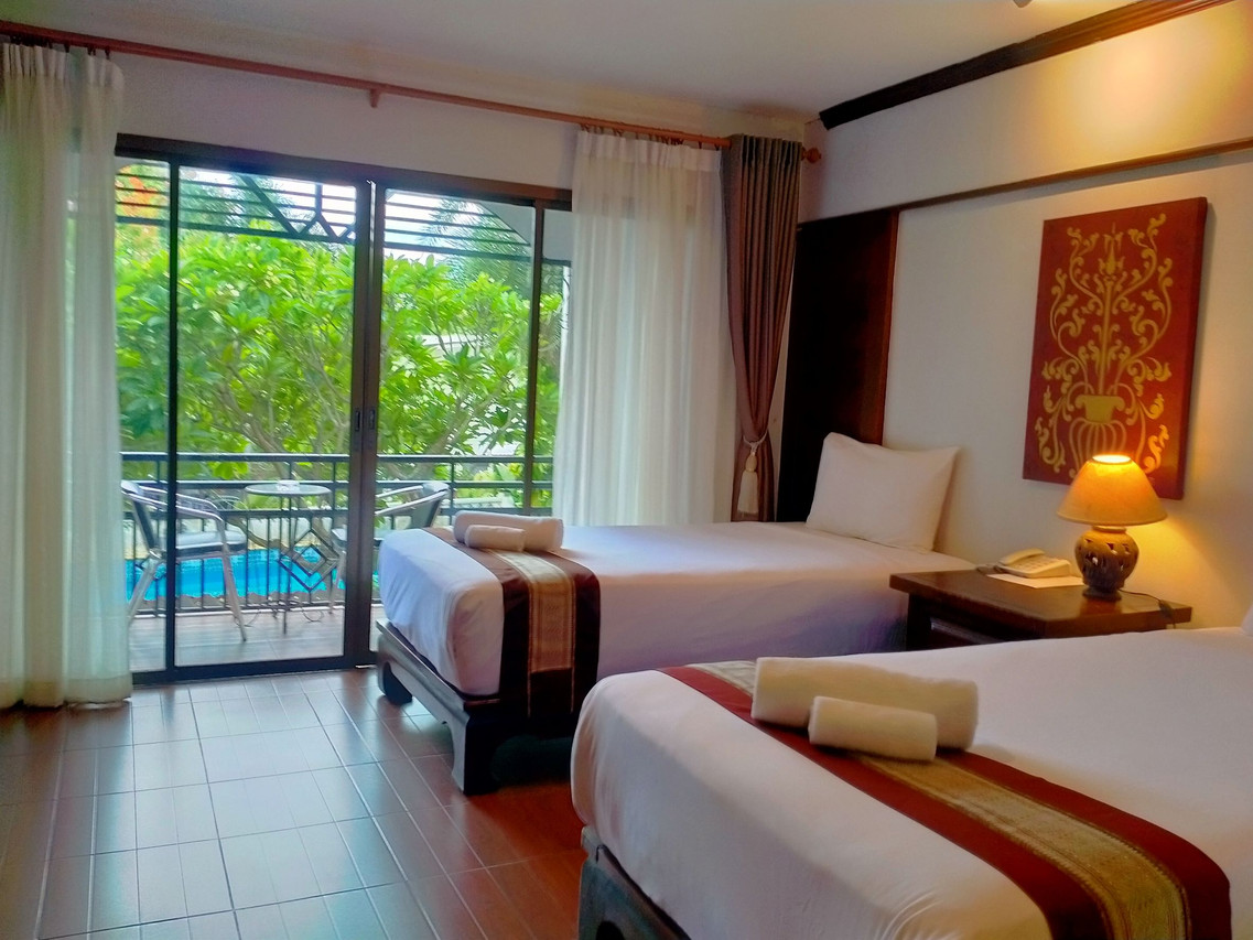 ห้องพักเตียงคู่ของ Phoomthai Garden Hotel แพร่ มีระเบียงส่วนตัวมองลงสระว่ายน้ำและสวน