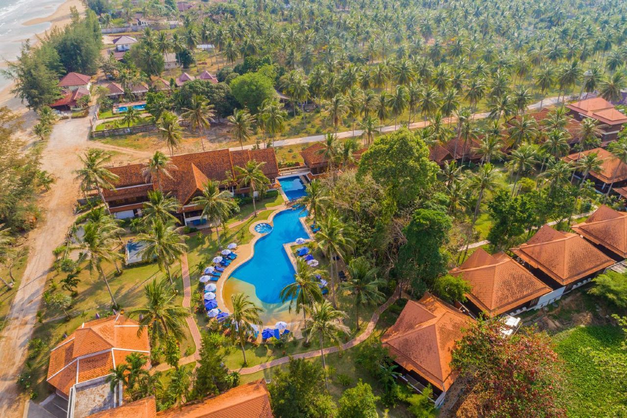 มุมสูงแสดงสระว่ายน้ำและบังกะโลหลังคาจั่วในสวนมะพร้าวของ Coral Hotel Bangsaphan