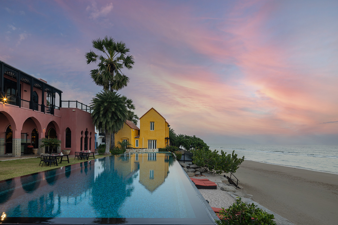 สระ infinity ริมทะเลของ Villa Maroc ยามพระอาทิตย์ตก กับอาคารสีชมพูและเหลือง