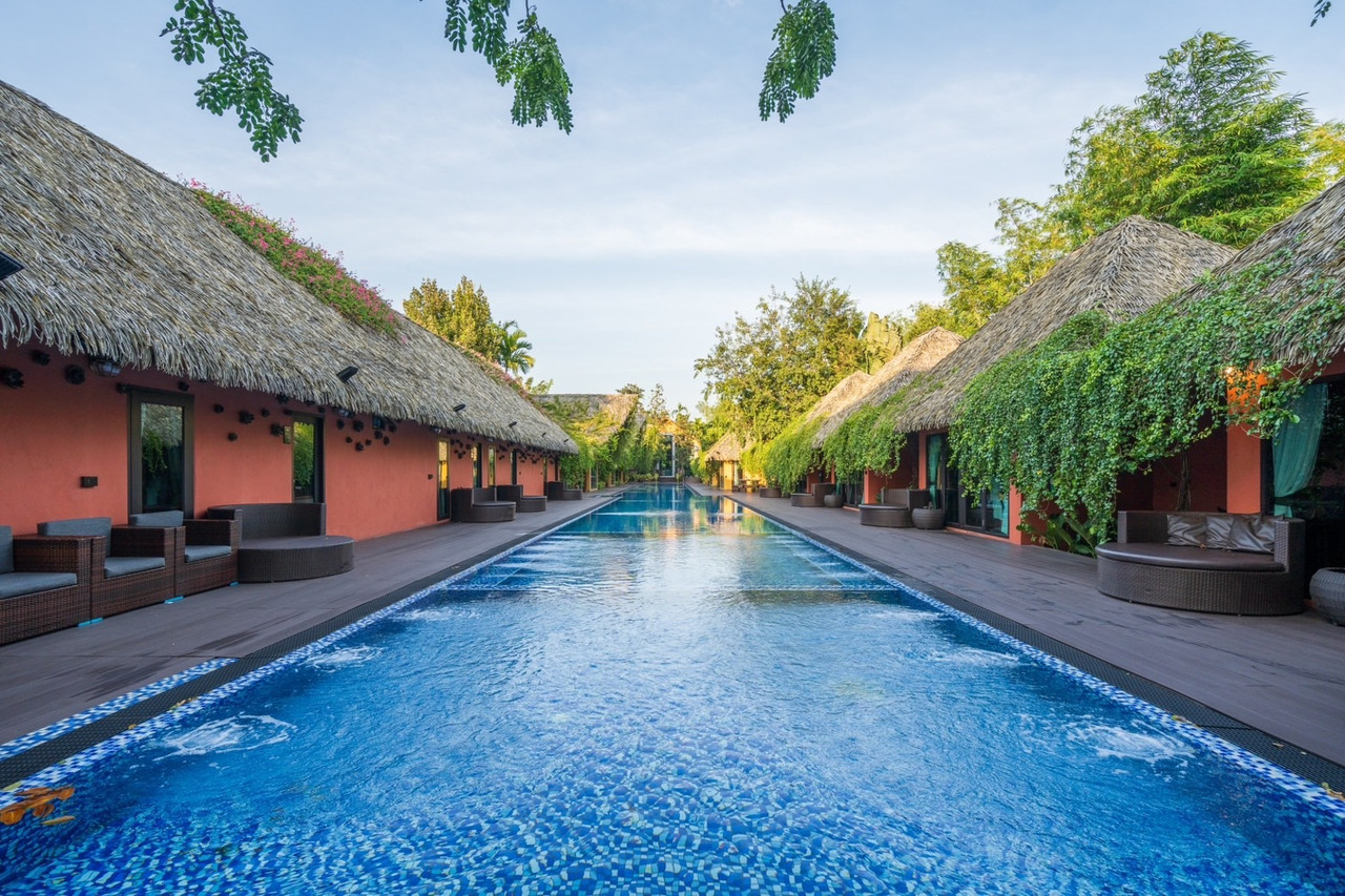 สระว่ายน้ำยาว 70 เมตรขนาบด้วยวิลล่าหลังคามุงจากที่ Khum Damnoen Resort