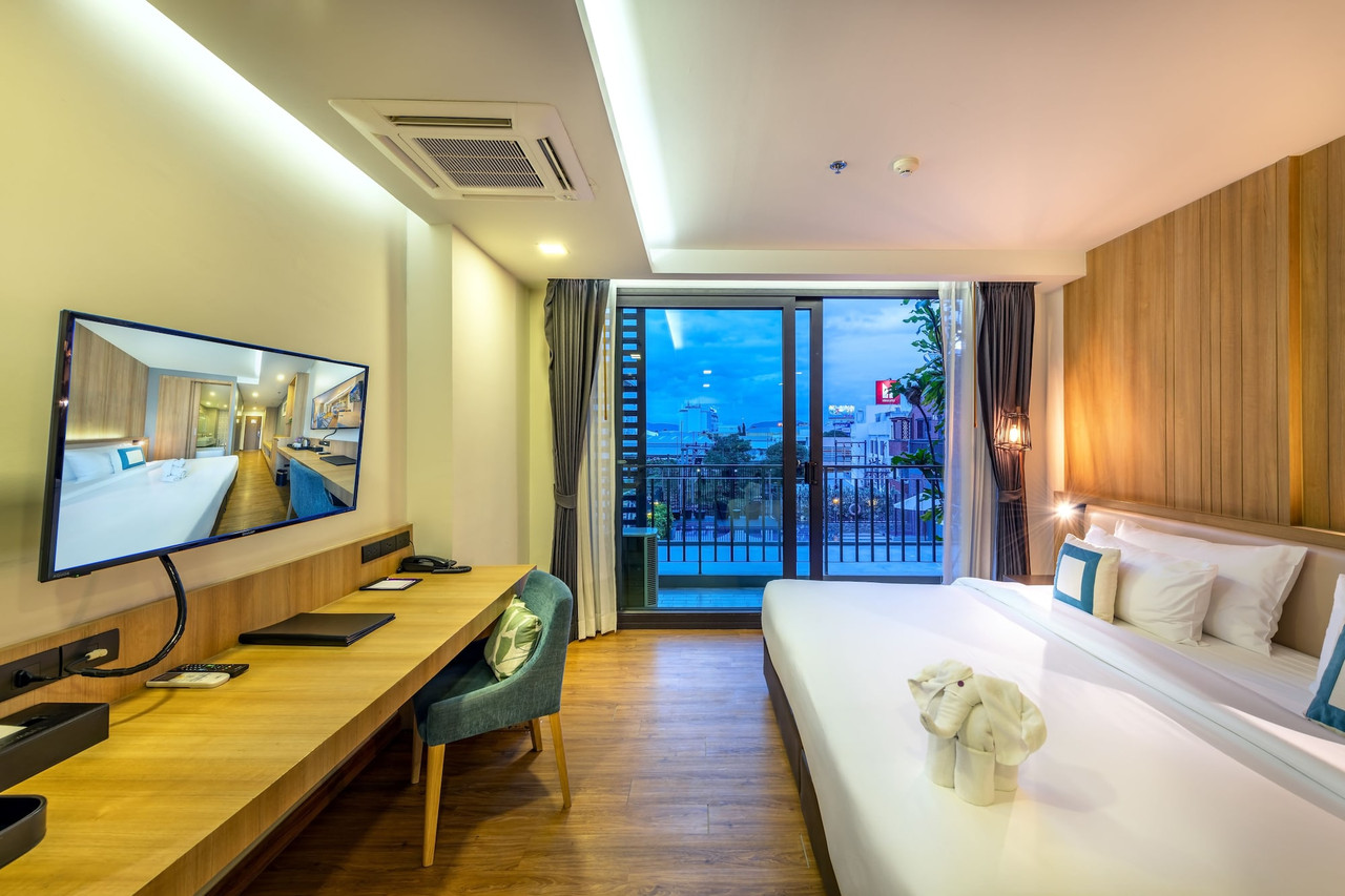 Warm wood-toned guest room with balcony, city view and flat-screen TV