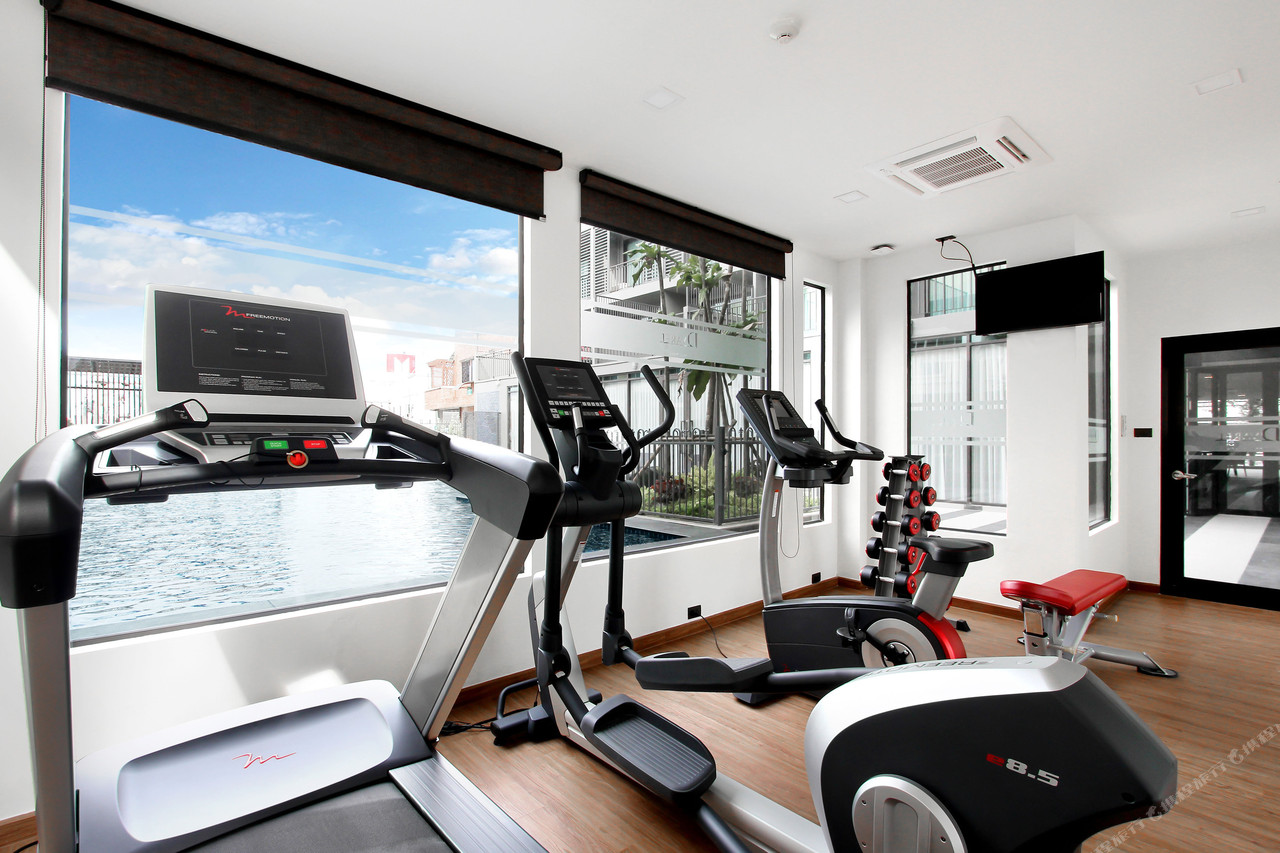 Gym beside floor-to-ceiling windows overlooking the pool