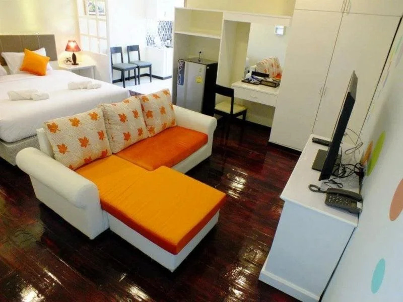 ห้องสตูดิโอของ Thanasiri Hotel พื้นไม้สีเข้ม มีโซฟาเบดสีส้ม ครัวเล็กและตู้เย็น
