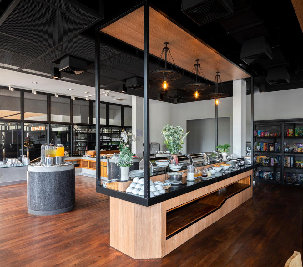 พื้นที่อาหารเช้าและคาเฟ่ Big Bite ตกแต่งด้วยโคมไฟล้อจักรยานและชั้นบอร์ดเกม