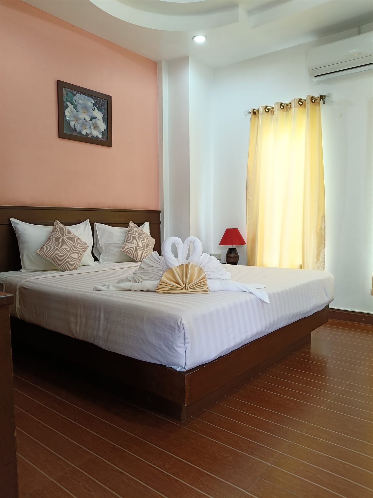 ห้องนอนผนังสีชมพูของ The Luxury สกลนคร เตียงใหญ่ พับผ้าเช็ดตัวเป็นรูปหงส์