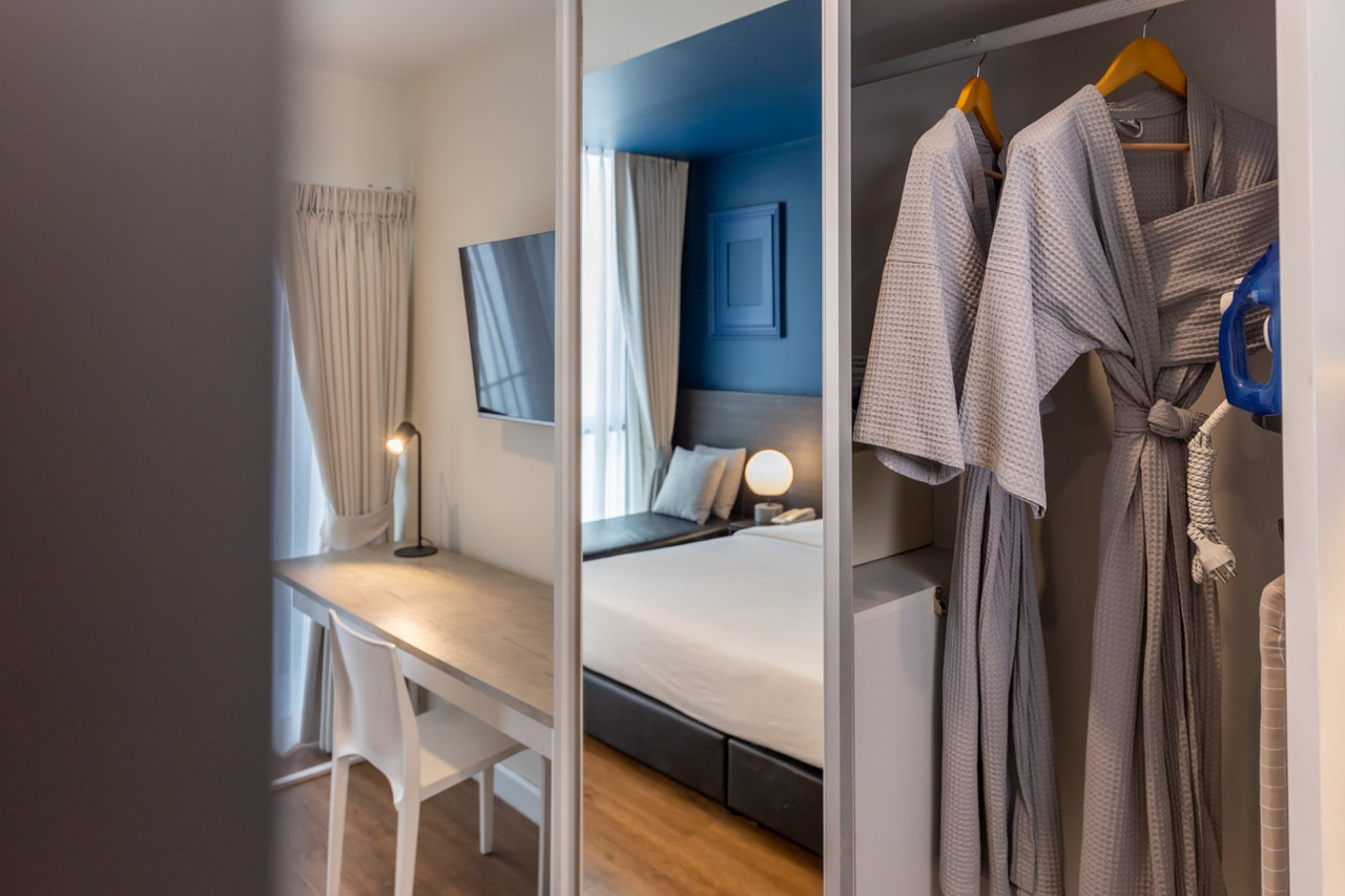 Blue Hippo Hotel guest room in blue tones with a work desk and wardrobe with robes