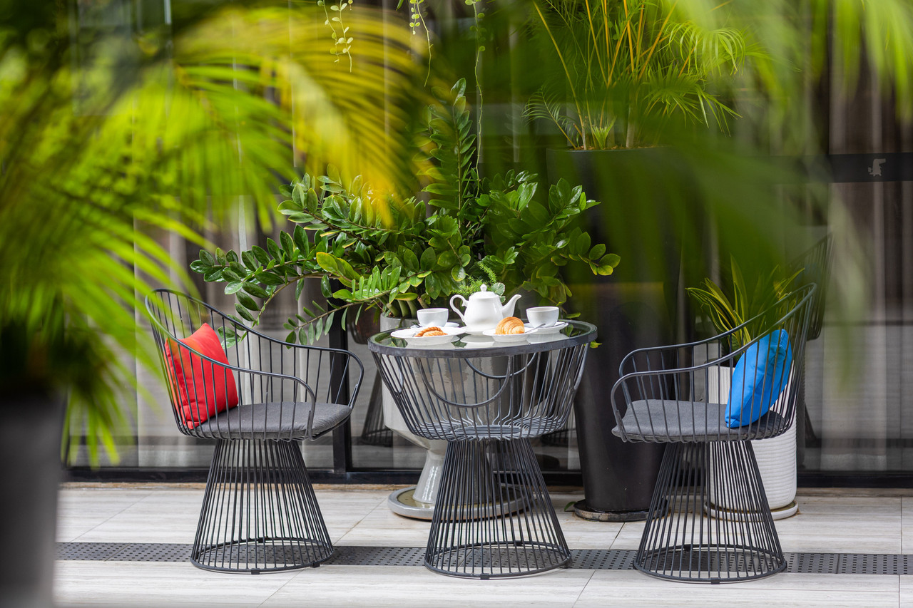 Outdoor café seating in the garden with metal chairs and blue and red cushions