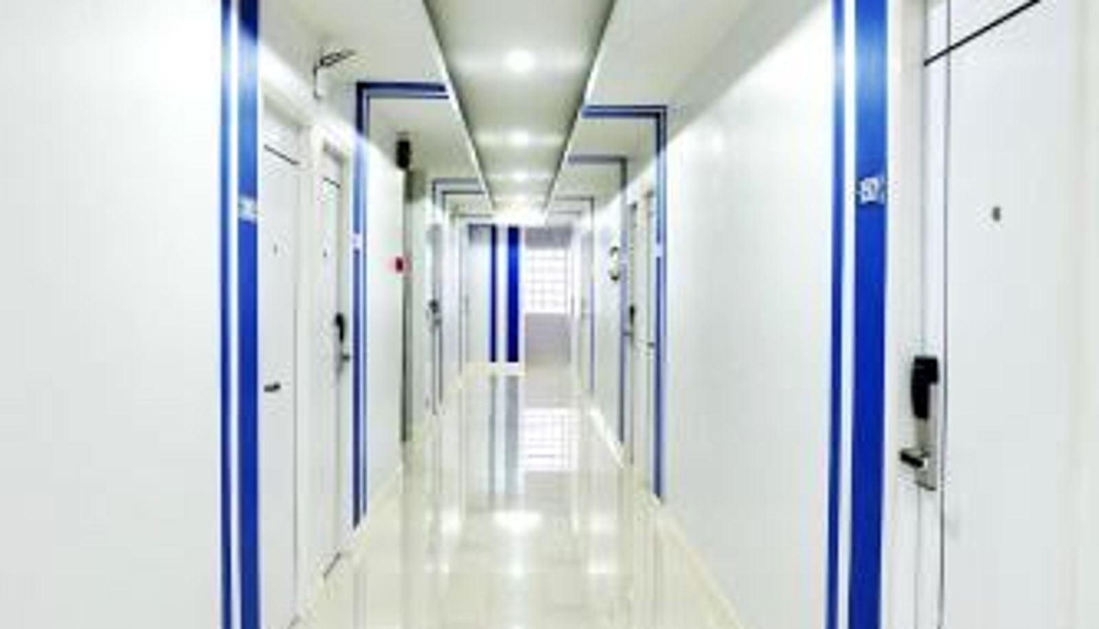ทางเดินภายในโรงแรมประตูขอบสีน้ำเงิน พื้นกระเบื้องขาวสะอาดที่ THE SEAPORT Hotel