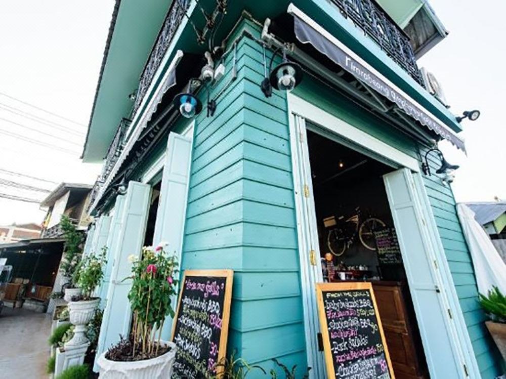 Turquoise wooden facade of Baanrabiang on the Amphawa canal with the cafe entrance downstairs