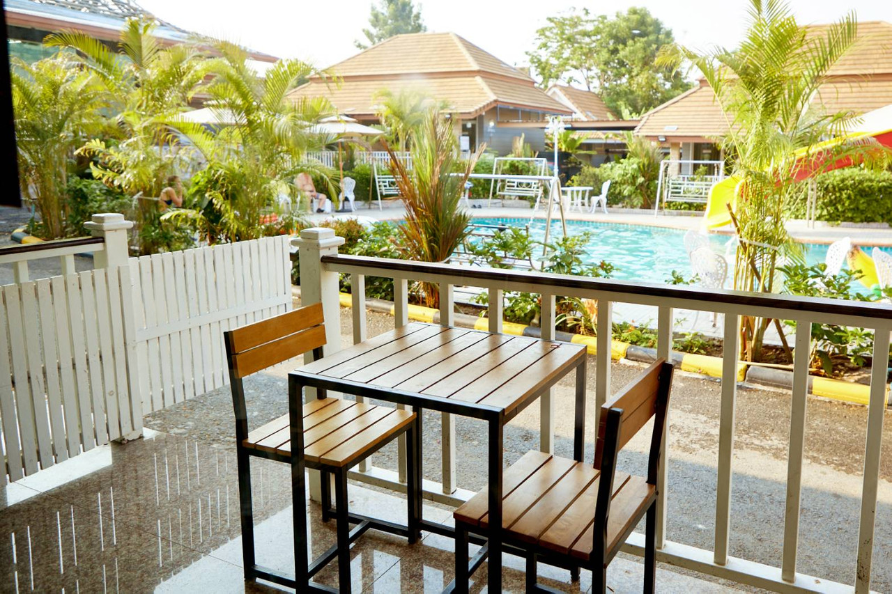 ระเบียงโต๊ะไม้มองออกไปเห็นสระว่ายน้ำกลางแจ้งและบังกะโลของ Baan Dara Resort