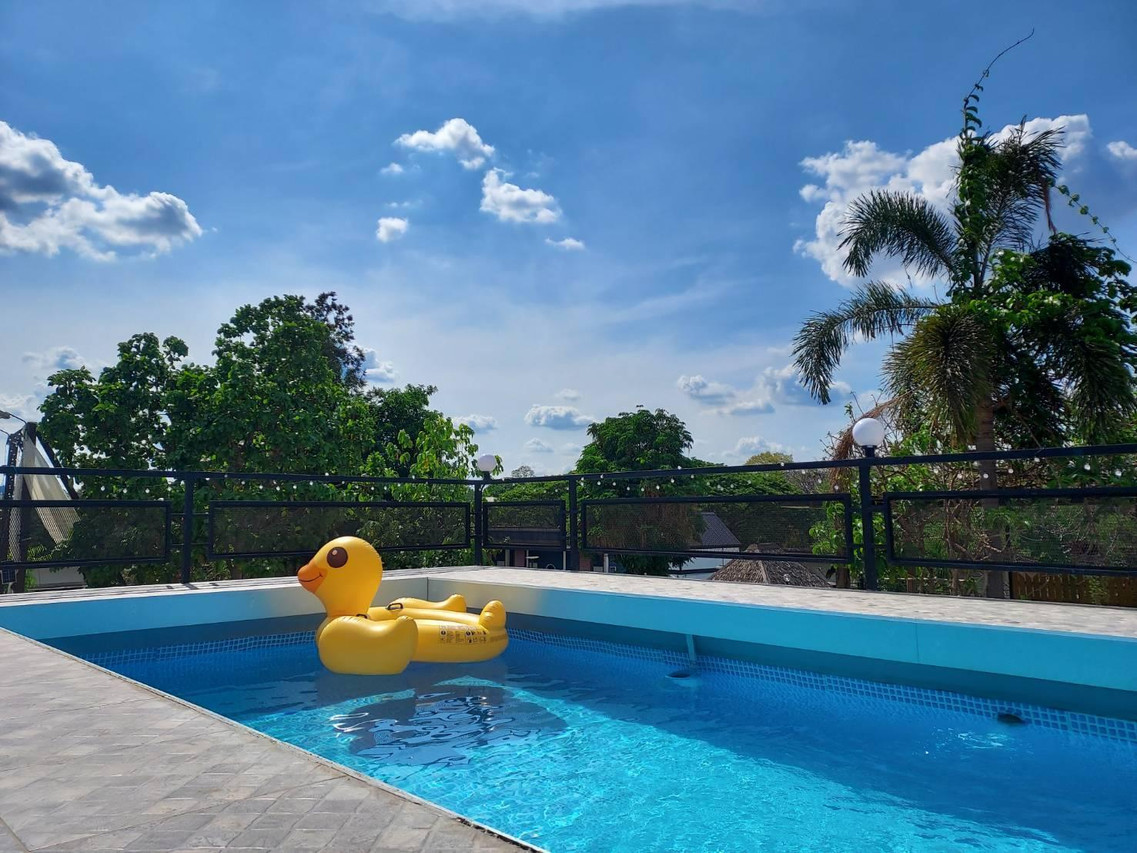 Outdoor pool at Maai Horm Boutique Resort backed by trees and sky