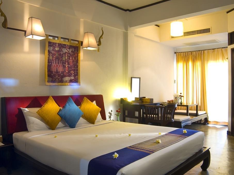 Guest room with teak furniture, hand-woven textiles and bright silk cushions
