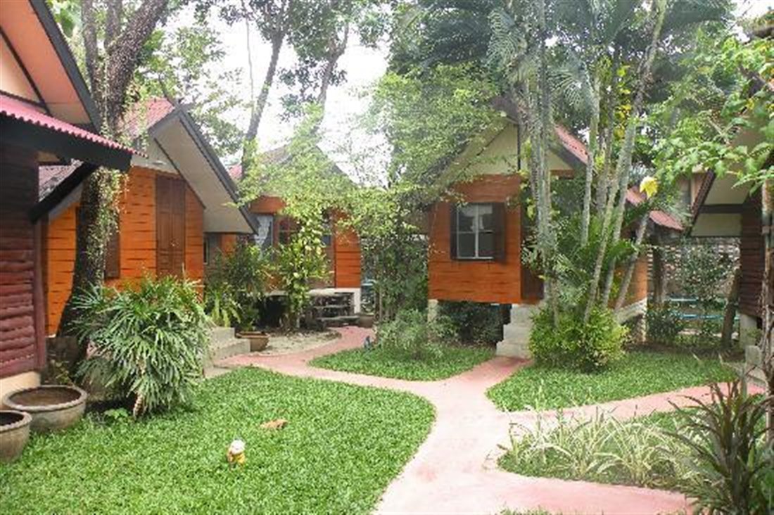 แถวบังกะโลไม้และทางเดินในสวนเขียวที่ Ban Thai Guesthouse