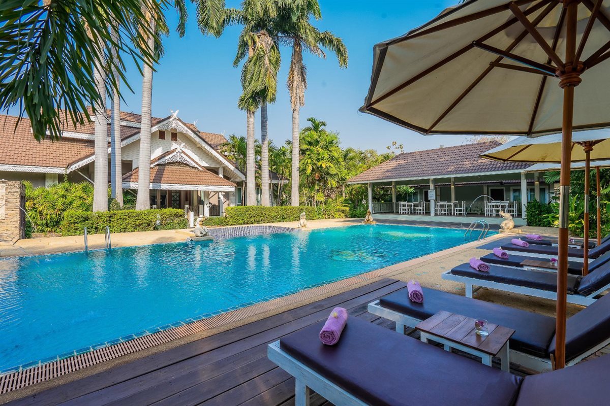 สระว่ายน้ำกลางแจ้งของ Le Charme Sukhothai กับเก้าอี้อาบแดดริมสระ