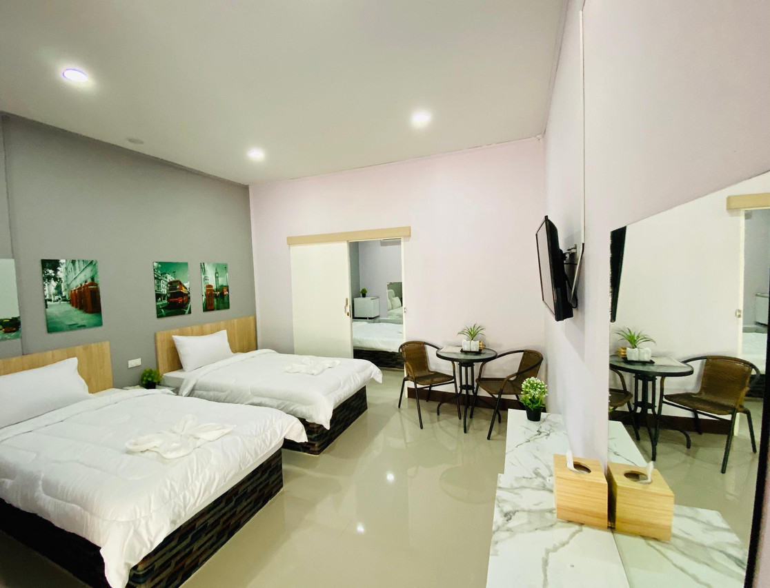 ห้องพักครอบครัวโทนขาว-เทา เตียงคู่ ผ้าปูขาวสะอาด มุมนั่งเล่นและทีวีจอแบน