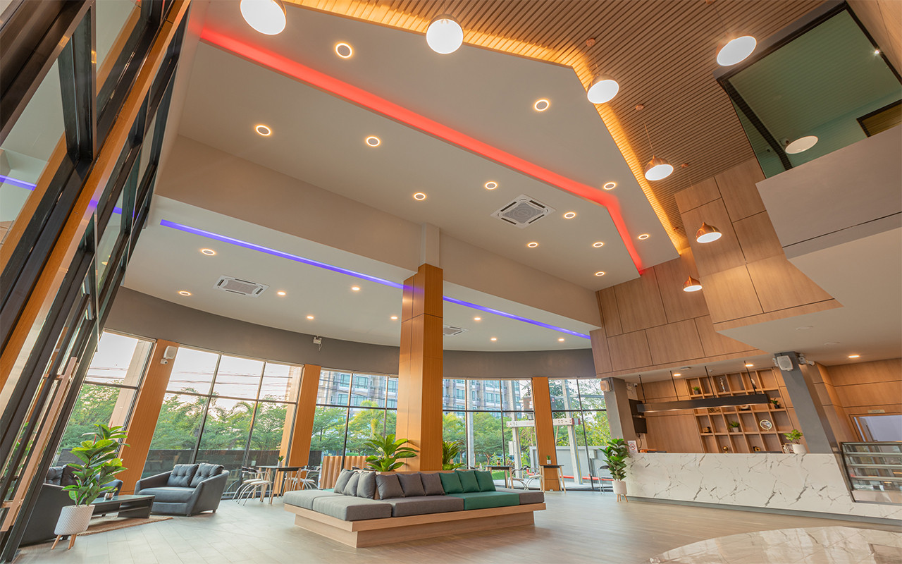 Double-height lobby with neon ceiling lighting and lounge seating by the windows
