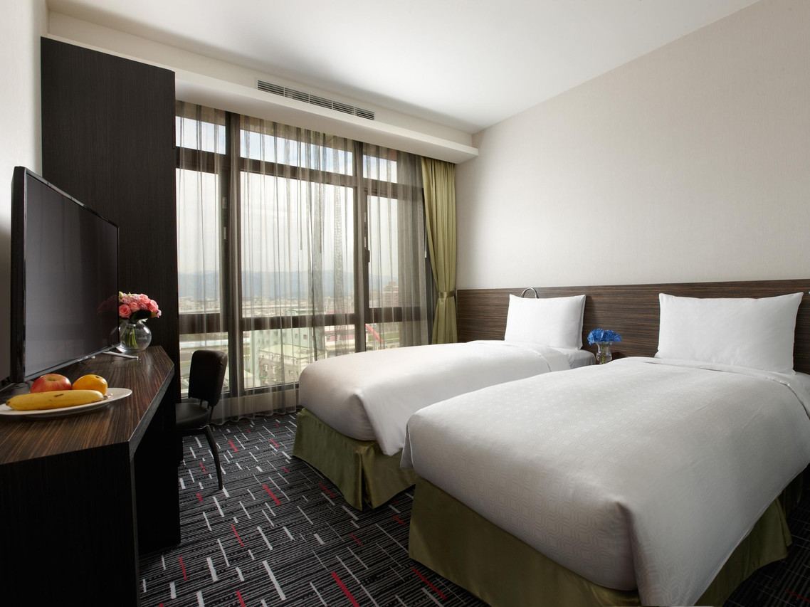 Capital Hotel Songshan twin room with large city-view windows and patterned carpet