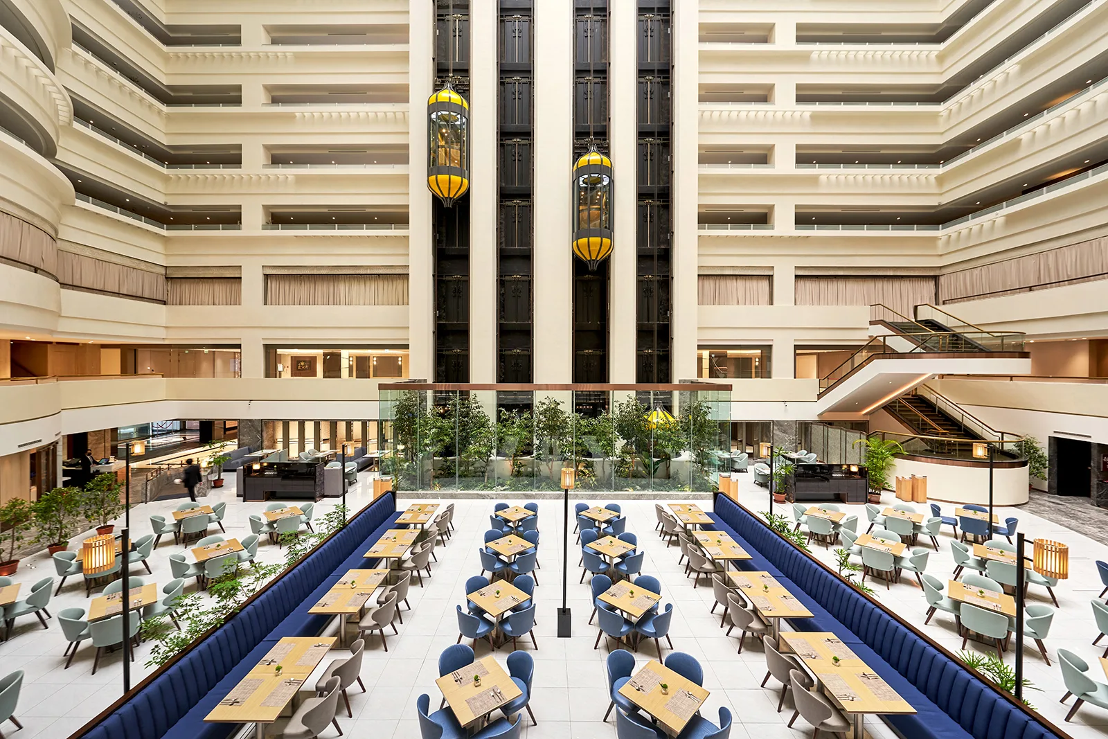 ILLUME Taipei's grand atrium lobby with gold capsule lifts and a multi-storey glass skylight