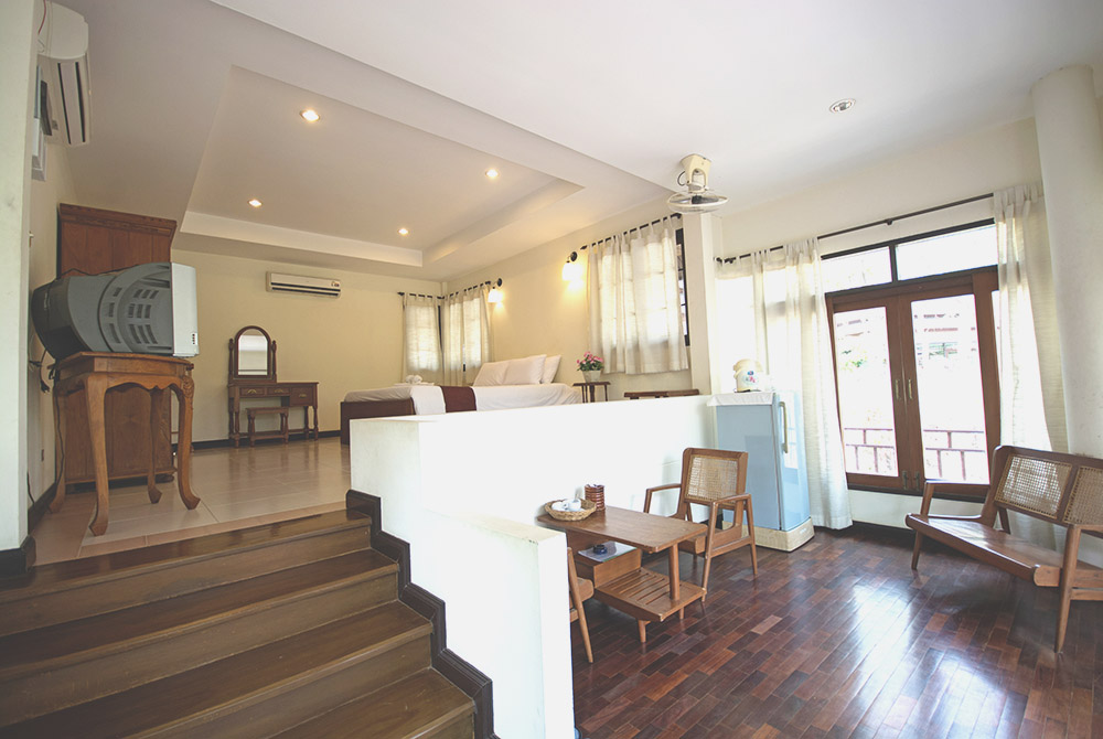 ห้องวิลล่าภายในกว้างแบบยกพื้น พื้นไม้ มุมนั่งเล่นเก้าอี้หวาย Tak Andaman Hotel