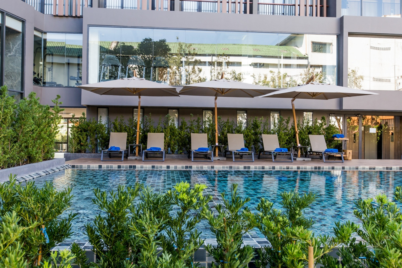 สระว่ายน้ำกลางแจ้งพร้อมร่มและเก้าอี้ผ้าใบ The Teak Hotel แม่สอด