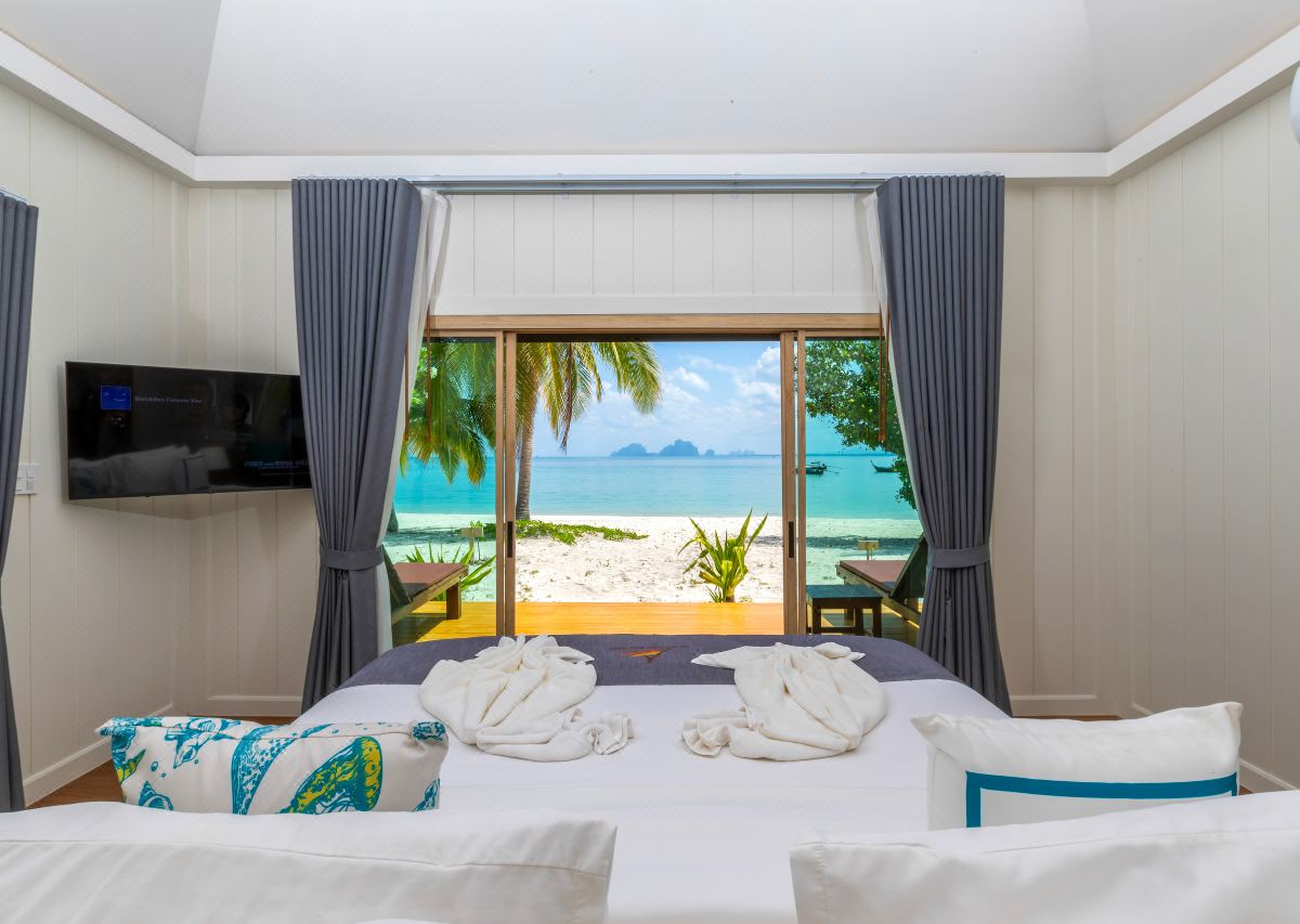 Villa interior with sliding doors open onto white sand and limestone islands at sea