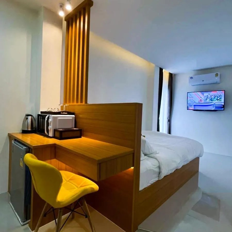 ห้องพัก TJ Boutique Hotel อุทัยธานี เตียงนอน โต๊ะไม้ ตู้เย็นเล็กและเก้าอี้สีเหลือง