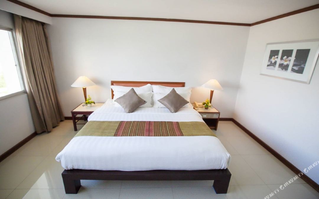 ห้องนอนเตียงใหญ่ Friday Hotel Uttaradit มีผ้าลายไทยคาดเตียง
