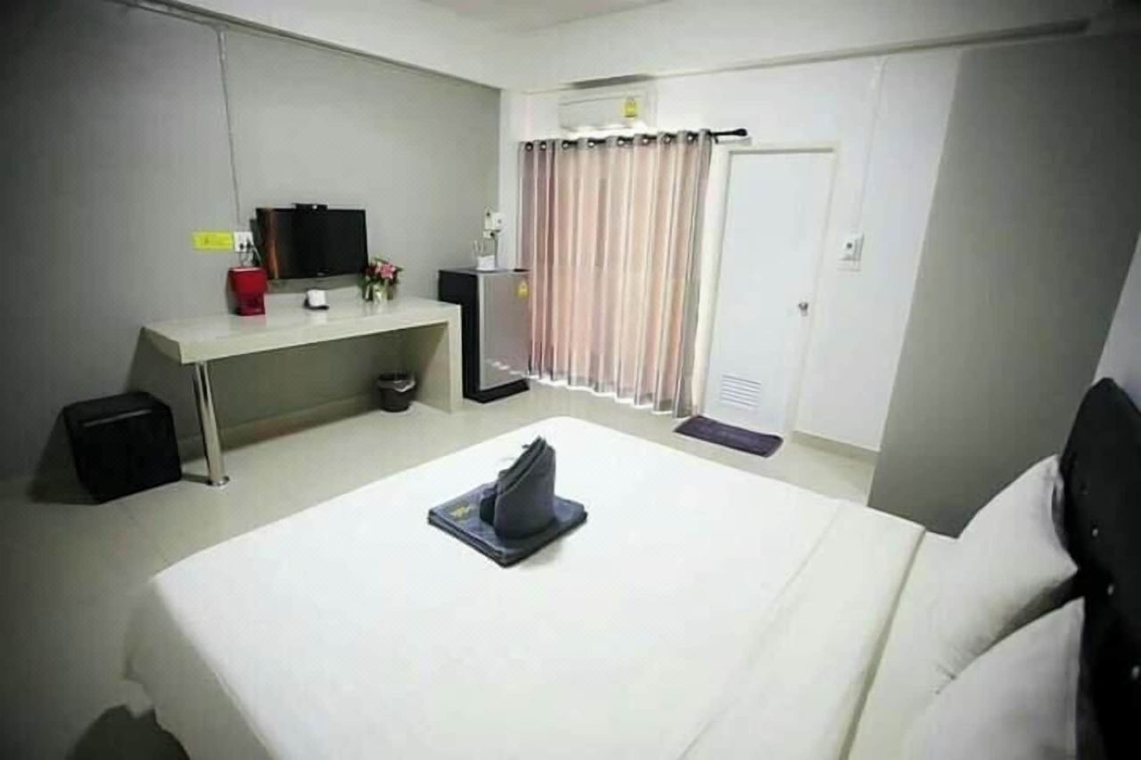 ห้องพักเตียงใหญ่ มีโต๊ะ ทีวี ตู้เย็น และประตูระเบียง